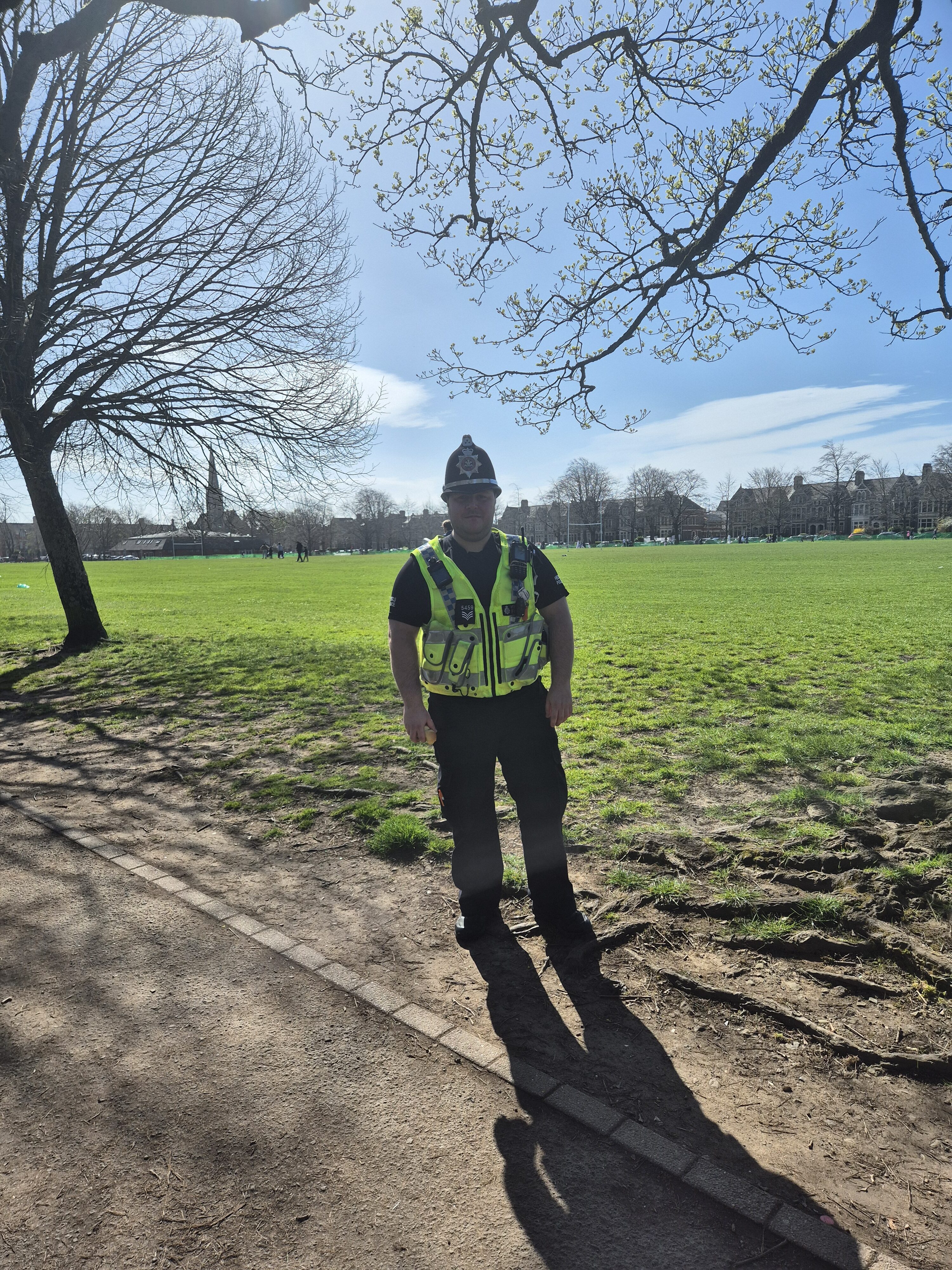 Police officer, and BSL learner, Bleddyn Jones stood in a park in the sunshine